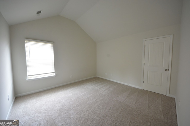 carpeted spare room with vaulted ceiling