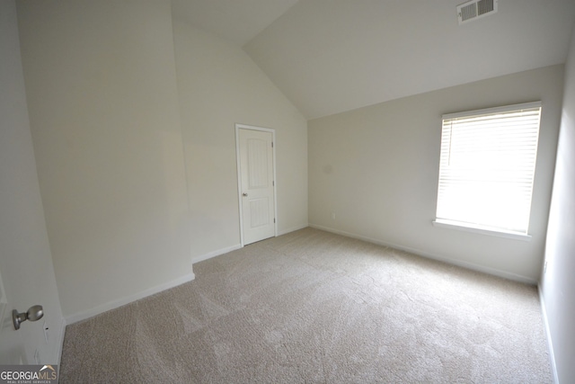 carpeted spare room featuring lofted ceiling