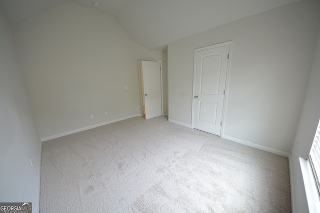 spare room featuring vaulted ceiling and light colored carpet