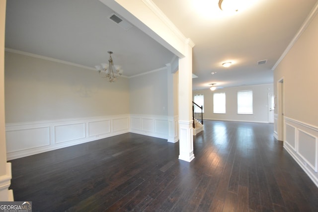 spare room with ornamental molding, an inviting chandelier, and dark hardwood / wood-style floors