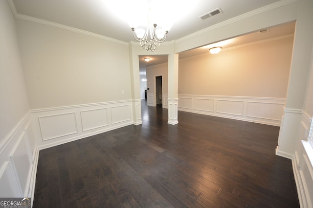 spare room with ornate columns, ornamental molding, a chandelier, and dark hardwood / wood-style floors