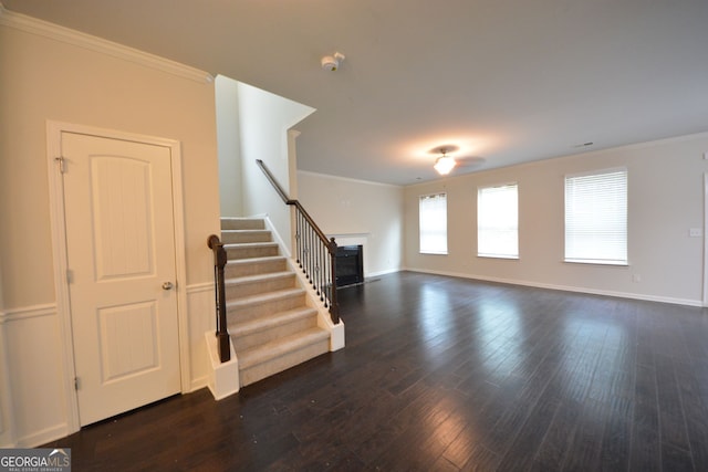 interior space featuring dark wood-type flooring, ornamental molding, and ceiling fan