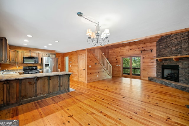 kitchen featuring sink, light hardwood / wood-style floors, kitchen peninsula, and black appliances