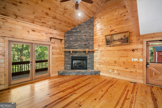 unfurnished living room with high vaulted ceiling, wooden walls, a fireplace, and wood-type flooring