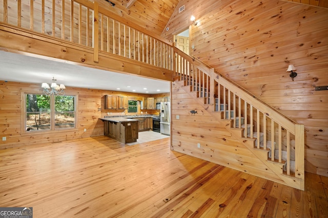 stairs with wood walls, a chandelier, wooden ceiling, hardwood / wood-style floors, and high vaulted ceiling