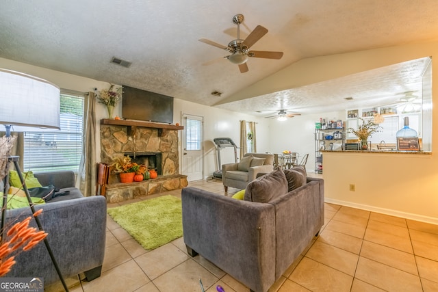 tiled living room with a stone fireplace, lofted ceiling, a textured ceiling, and ceiling fan