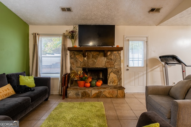 living room with a stone fireplace, a textured ceiling, and light tile patterned flooring