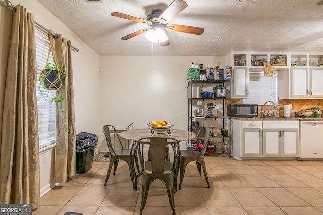 tiled dining space featuring ceiling fan, a textured ceiling, and sink