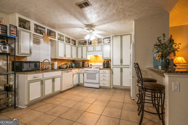 kitchen featuring white cabinets, white appliances, dark stone countertops, and ceiling fan