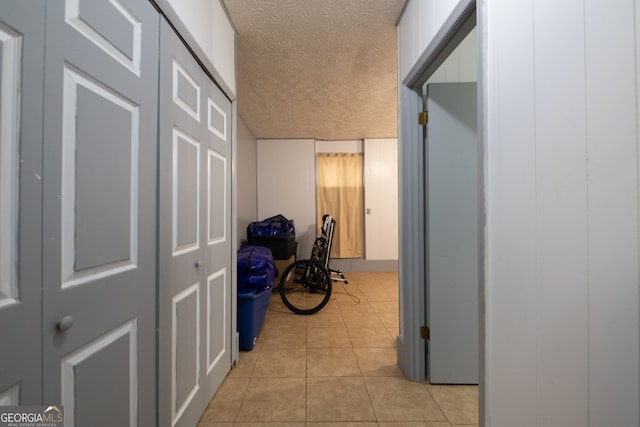 corridor featuring a textured ceiling and light tile patterned floors