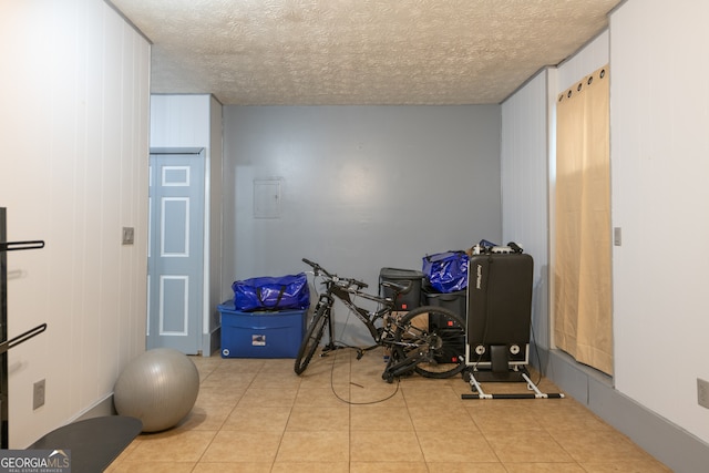 workout area featuring a textured ceiling and light tile patterned floors