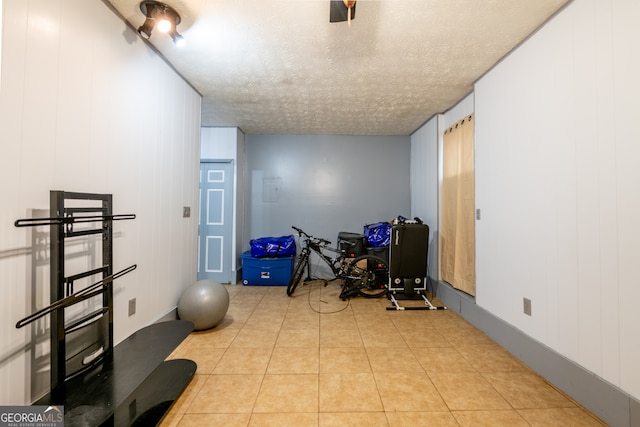 exercise area with a textured ceiling and light tile patterned floors