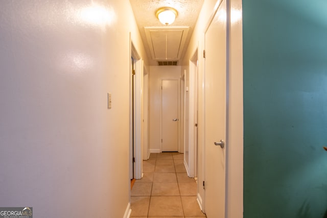 hall featuring a textured ceiling and light tile patterned floors