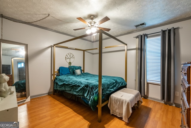 bedroom with a textured ceiling, wood-type flooring, and ceiling fan