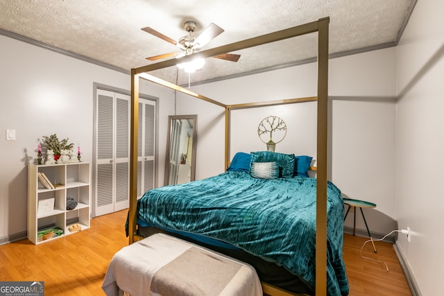 bedroom featuring hardwood / wood-style floors, ceiling fan, a textured ceiling, and ornamental molding