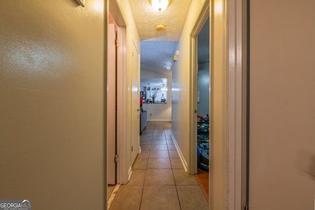 corridor featuring a textured ceiling and light tile patterned floors