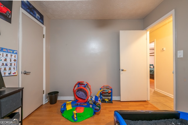 game room featuring wood-type flooring and a textured ceiling