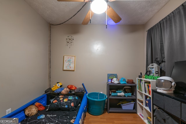 playroom featuring a textured ceiling, hardwood / wood-style flooring, and ceiling fan