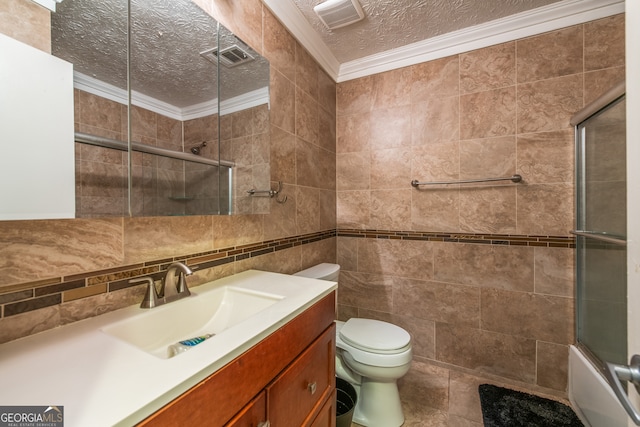 full bathroom featuring combined bath / shower with glass door, vanity, crown molding, toilet, and tile walls