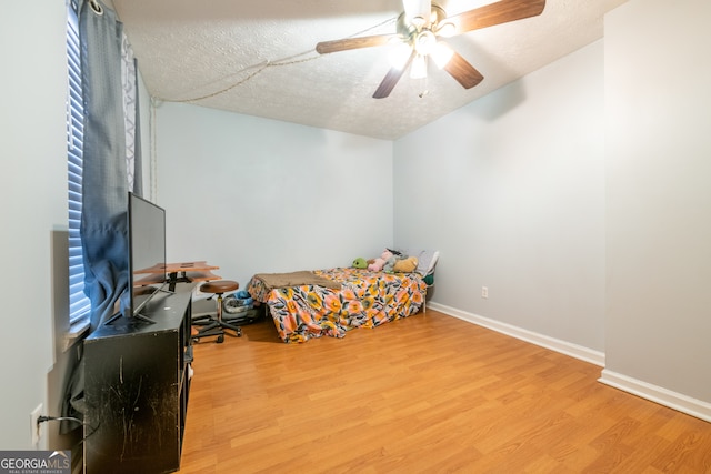 bedroom featuring hardwood / wood-style floors, a textured ceiling, and ceiling fan