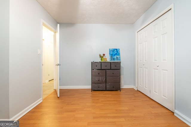 unfurnished bedroom with light hardwood / wood-style flooring, a textured ceiling, and a closet