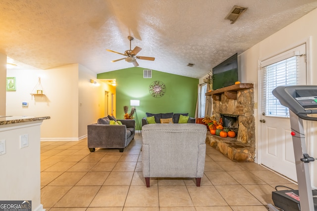 living room featuring a fireplace, a textured ceiling, light tile patterned floors, vaulted ceiling, and ceiling fan