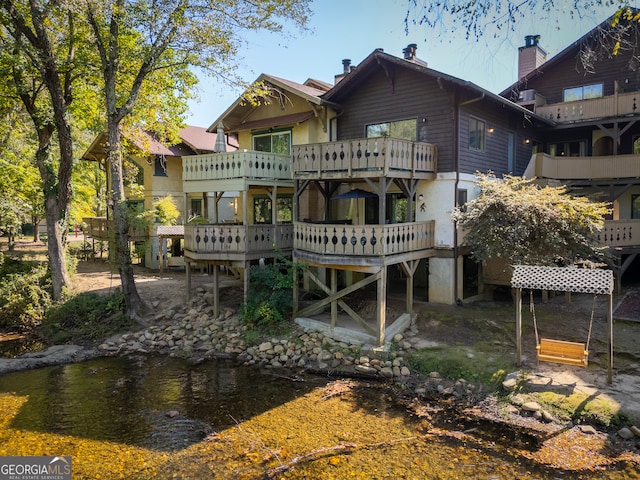 back of house with a balcony and a deck with water view