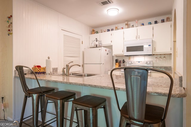 kitchen featuring white appliances, sink, light stone counters, decorative backsplash, and white cabinets