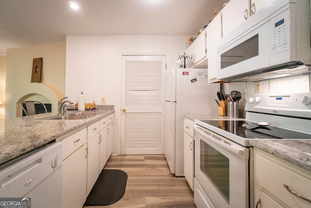 kitchen with light stone counters, white cabinets, white appliances, sink, and light hardwood / wood-style floors