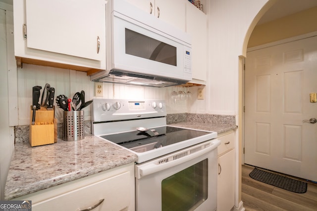 kitchen with tasteful backsplash, white appliances, white cabinets, and light hardwood / wood-style flooring