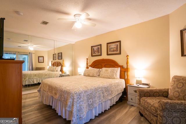 bedroom featuring ceiling fan, a textured ceiling, and dark hardwood / wood-style floors