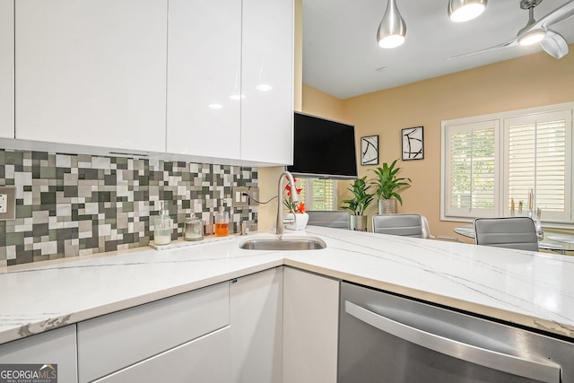 kitchen featuring white cabinetry, sink, backsplash, stainless steel dishwasher, and light stone countertops