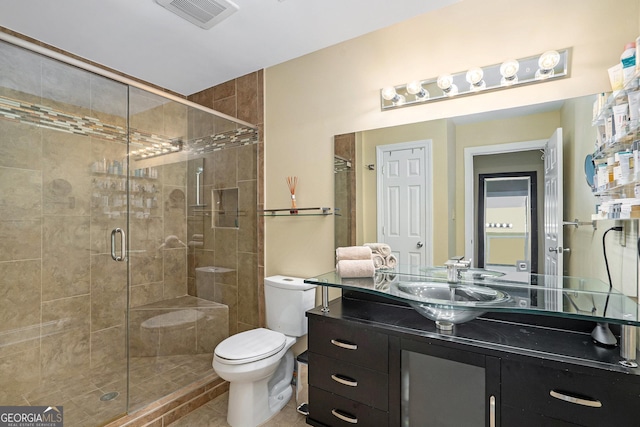 bathroom featuring tile patterned floors, vanity, toilet, and a shower with door