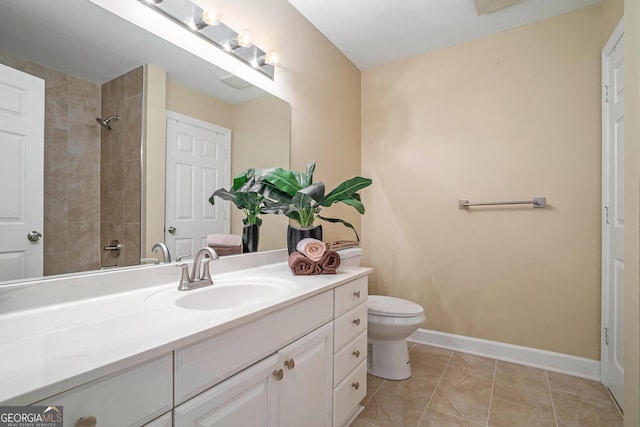 bathroom with a tile shower, vanity, tile patterned floors, and toilet