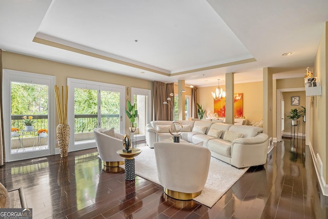 living room featuring a raised ceiling, dark wood-type flooring, and a notable chandelier