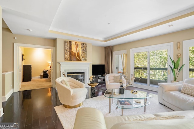 living room with a tray ceiling, a high end fireplace, and hardwood / wood-style flooring