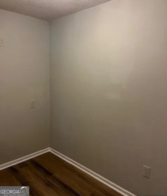 empty room featuring a textured ceiling and dark hardwood / wood-style flooring