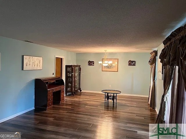 misc room with a chandelier, a textured ceiling, and dark hardwood / wood-style flooring