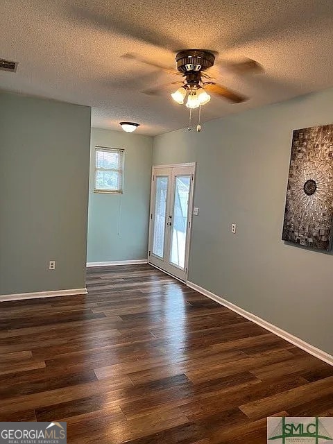 empty room with ceiling fan, dark hardwood / wood-style flooring, a textured ceiling, and french doors