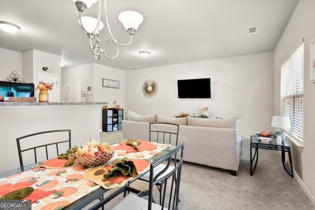 carpeted dining space with an inviting chandelier