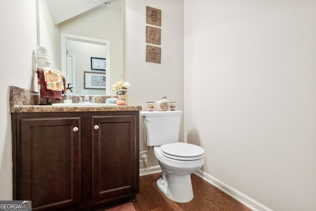 bathroom with hardwood / wood-style floors, vanity, and toilet