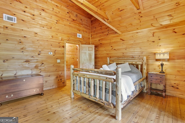 bedroom featuring wooden ceiling, beamed ceiling, light hardwood / wood-style flooring, and wooden walls