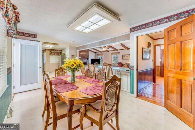 dining area featuring ornamental molding, light hardwood / wood-style flooring, and a textured ceiling