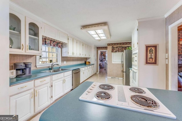 kitchen featuring white cabinets, ornamental molding, appliances with stainless steel finishes, and sink