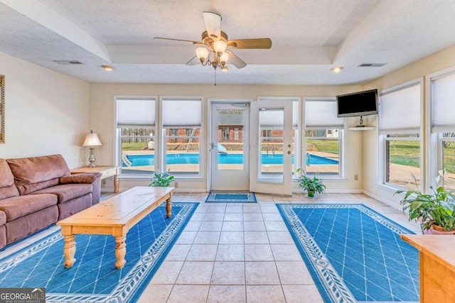 interior space with ceiling fan, a tray ceiling, and a textured ceiling