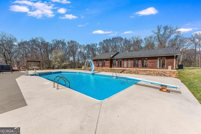 view of pool with a patio, a water slide, and a diving board