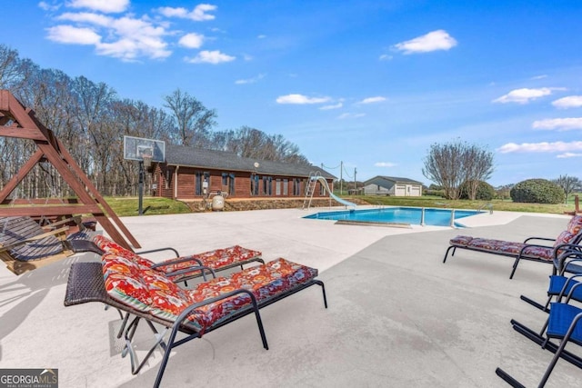 view of pool with a water slide and a patio