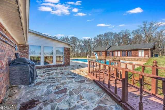 exterior space with a water slide, grilling area, and a patio area