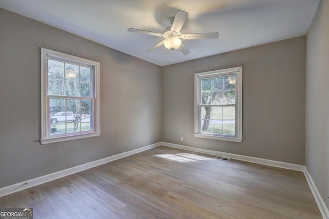 empty room with ceiling fan, a healthy amount of sunlight, and light wood-type flooring