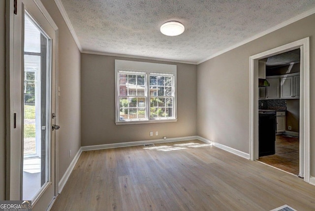 empty room with a textured ceiling, light hardwood / wood-style floors, and ornamental molding